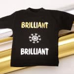 A shirt that reads "Brilliant" twice with a snowflake in Gold and Silver Brilliant DecoFilm with two rolls behind it