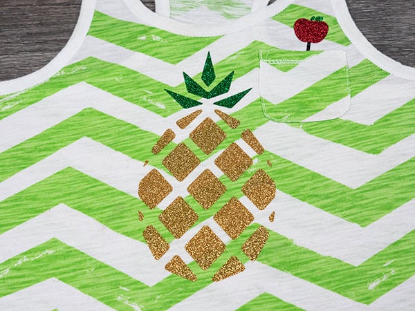 A pineapple and an apple pen pressed onto a tank top made with Light Gold, Emerald, and Red GlitterFlex® Ultra