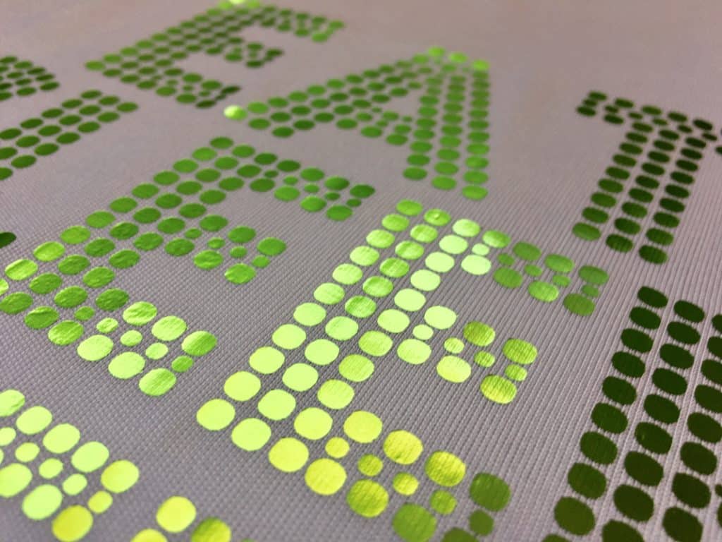 A close up of text pressed with Peridot Textile Foils- the close up show the shine on the material