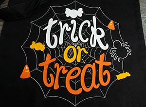 Image depicting the downloadable cut file that says "Trick or Treat" on a spider web with candy