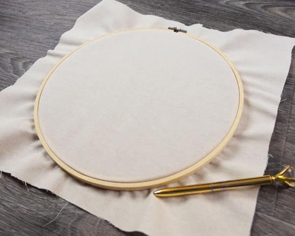 The hoop with the cloth in the middle pulled tight before we mark on the outside to measure where we're going to cut