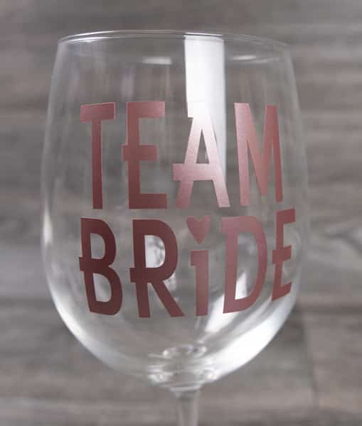 A wine glass that reads "Team Bride" in Rose Gold Craft Vinyl