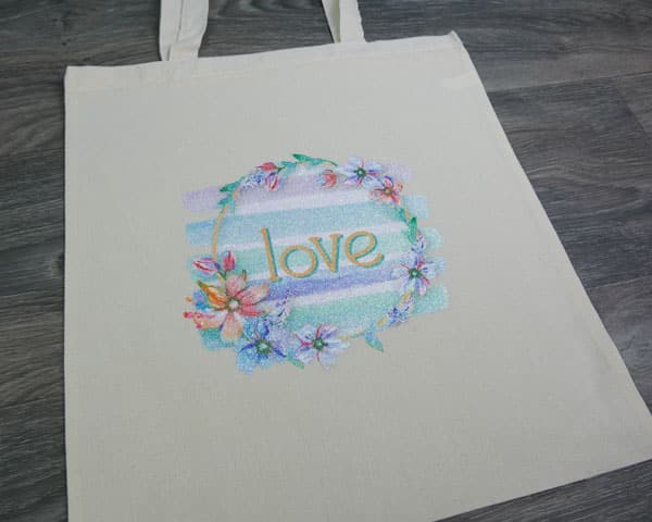 Shows a bag with the sublimated "love" design pressed onto it. The design is sublimated into GlitterFlex Ultra