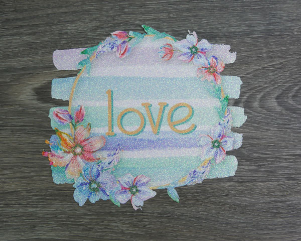 The love sublimation design pressed onto cut GlitterFlex Ultra before being pressed on a shirt