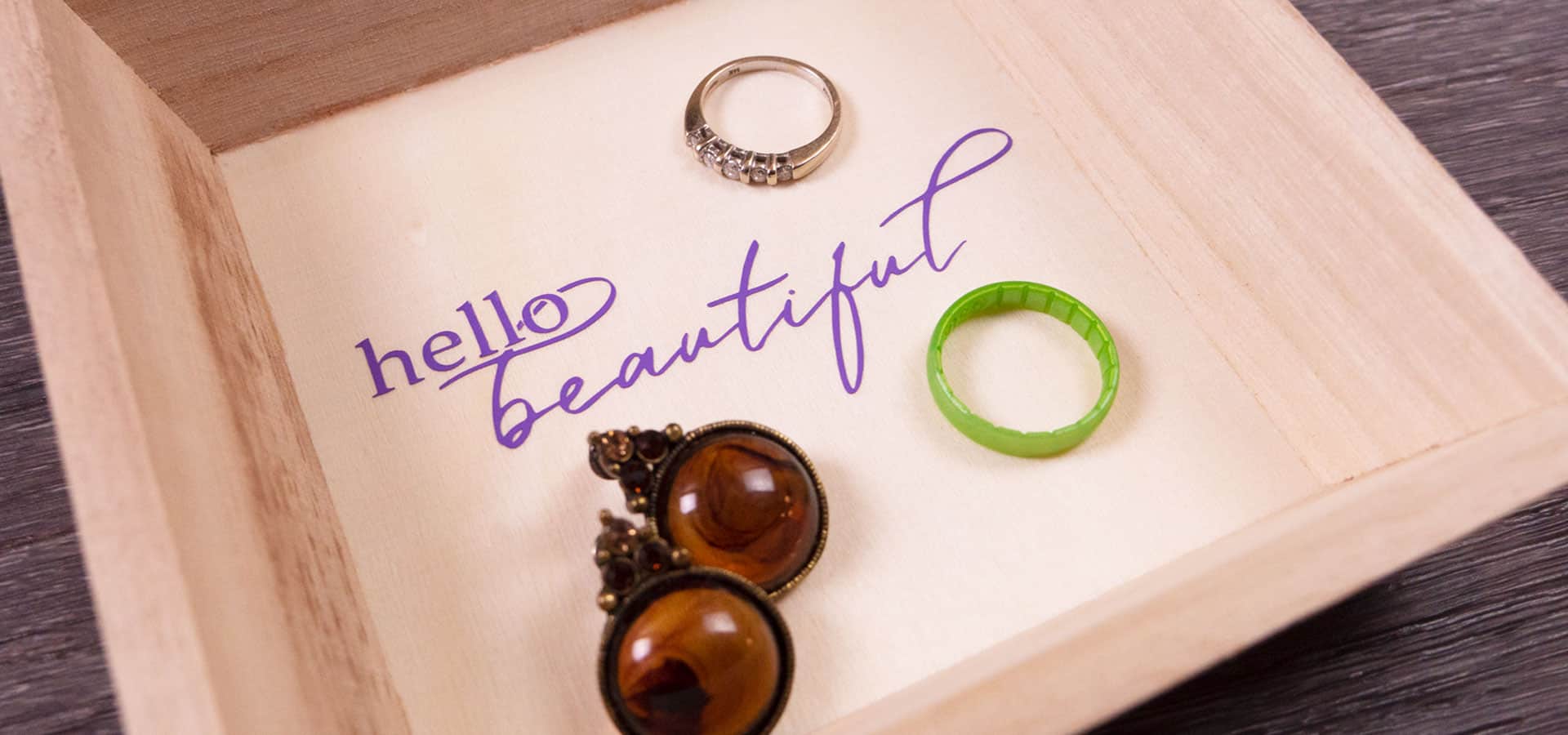 A wooden jewelry plate decorated with psv that says "Hello beautiful"